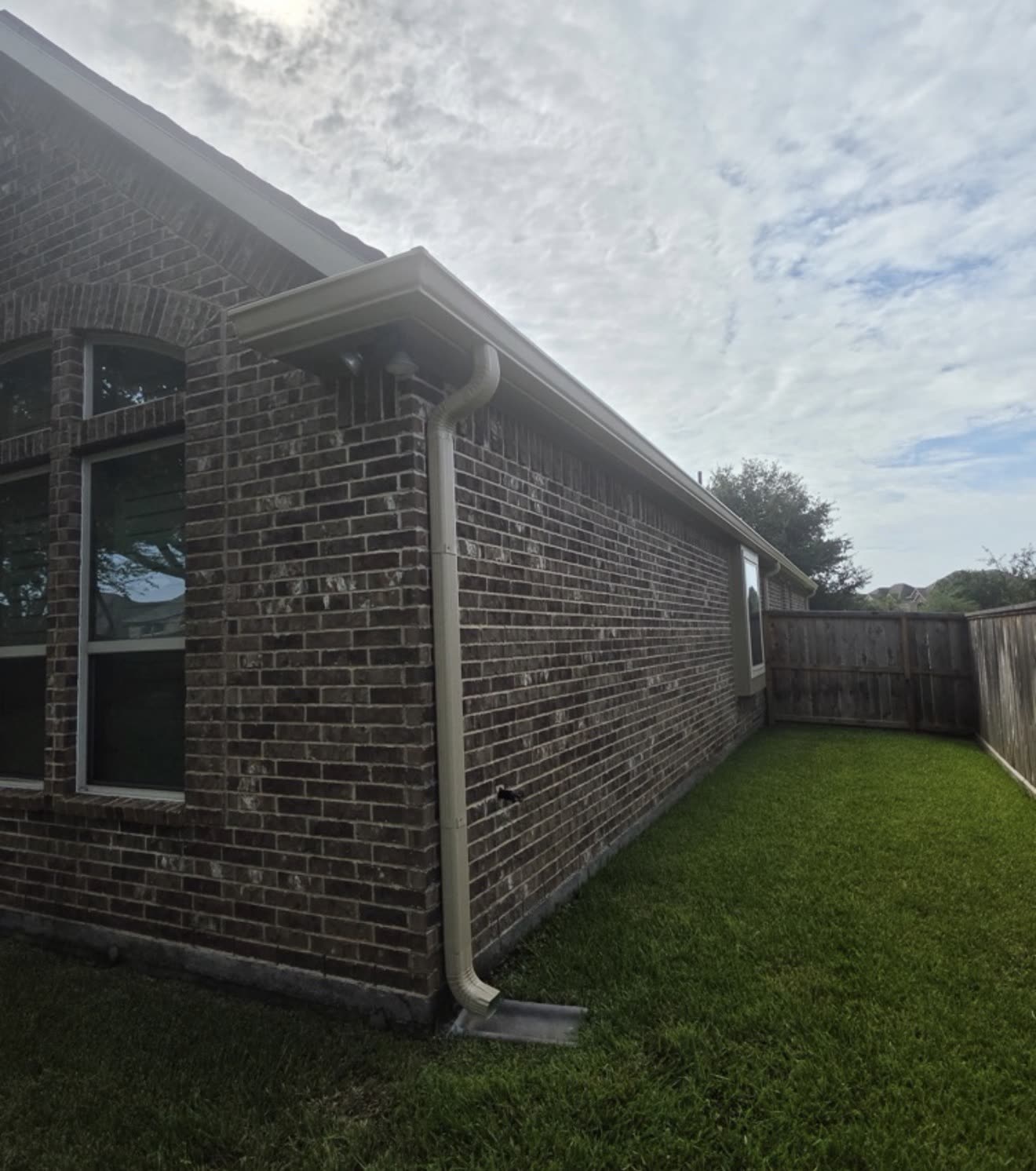 Seamless gutter and downspout on the side of a brick home