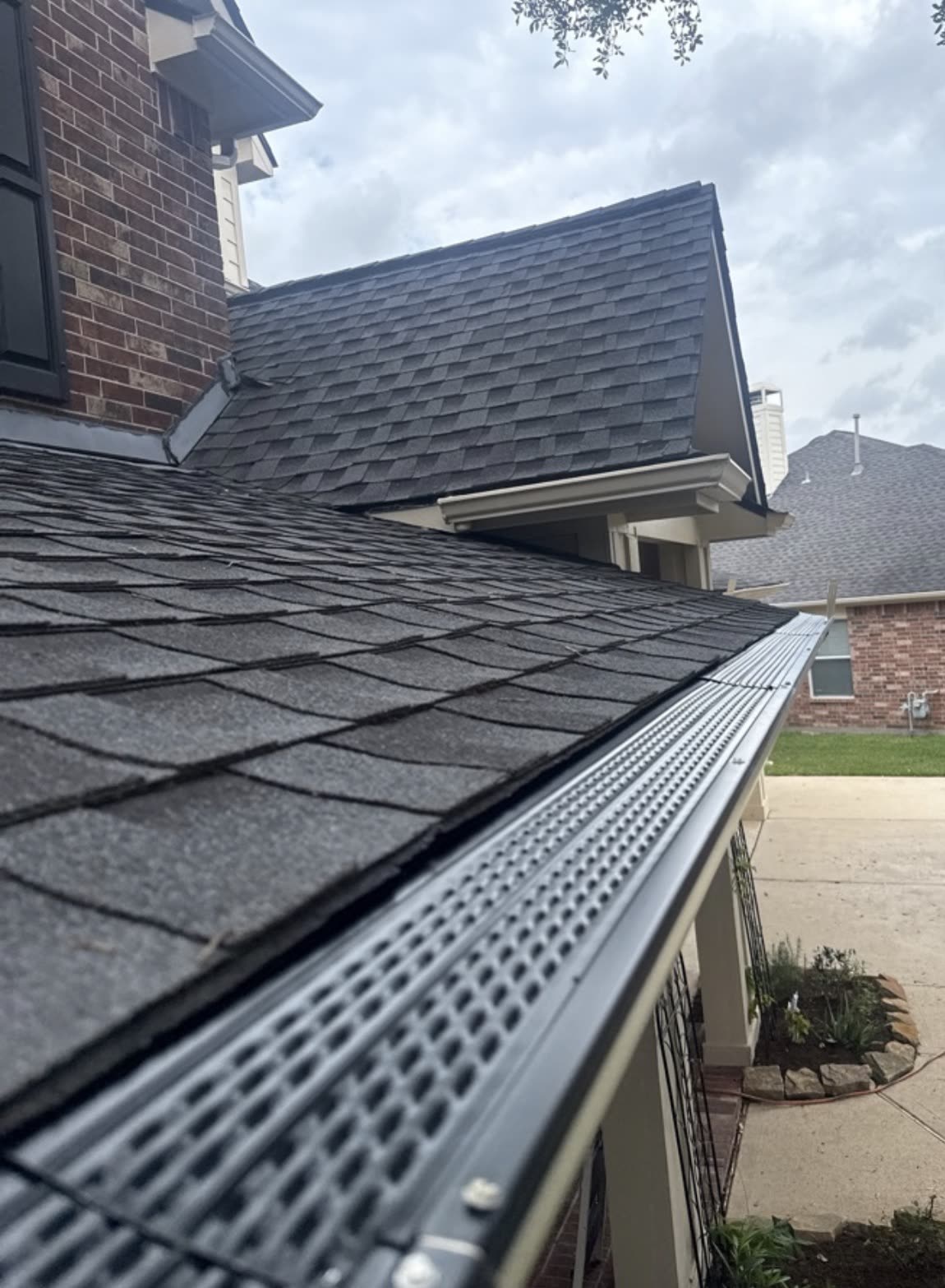 Gutter guard installed on a seamless gutter along a shingle roof