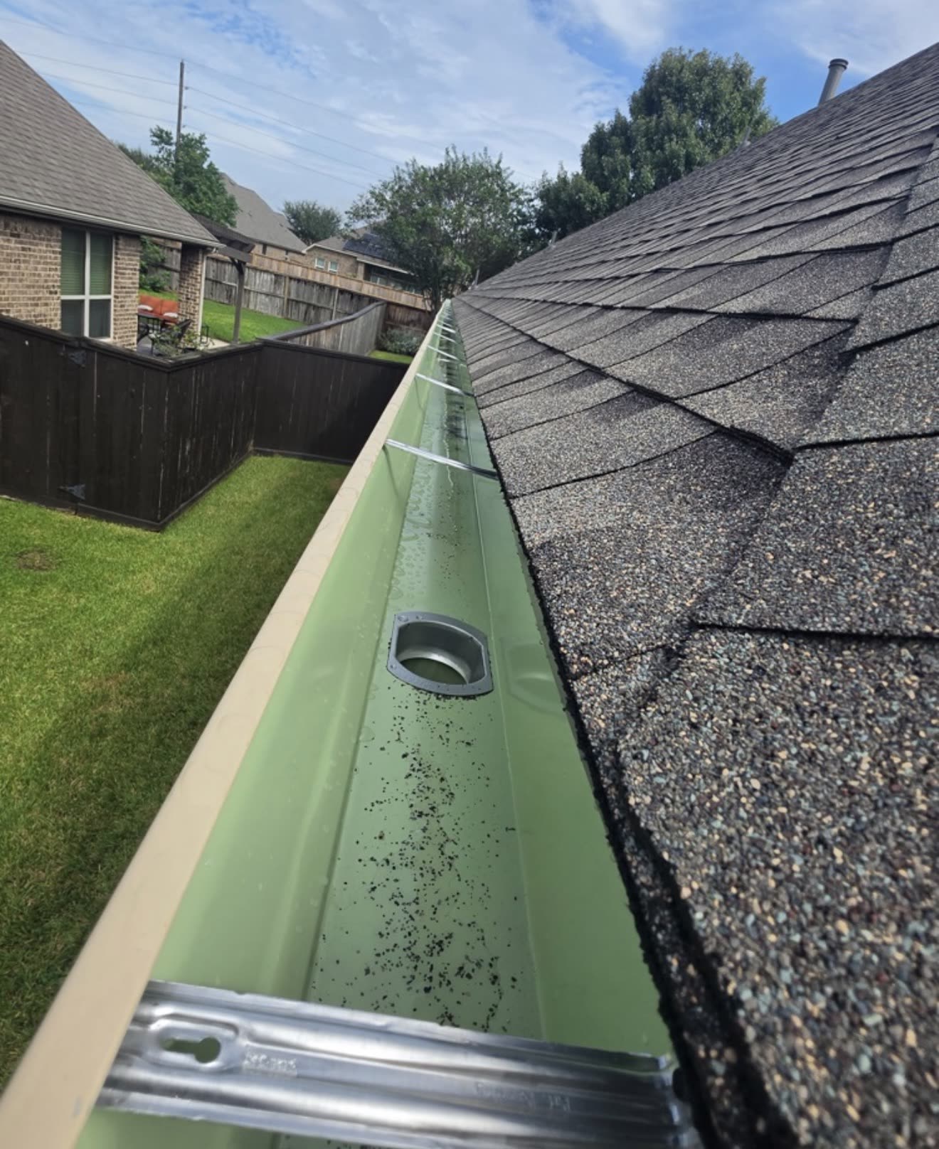 Inside view of a new seamless gutter along a shingle roof