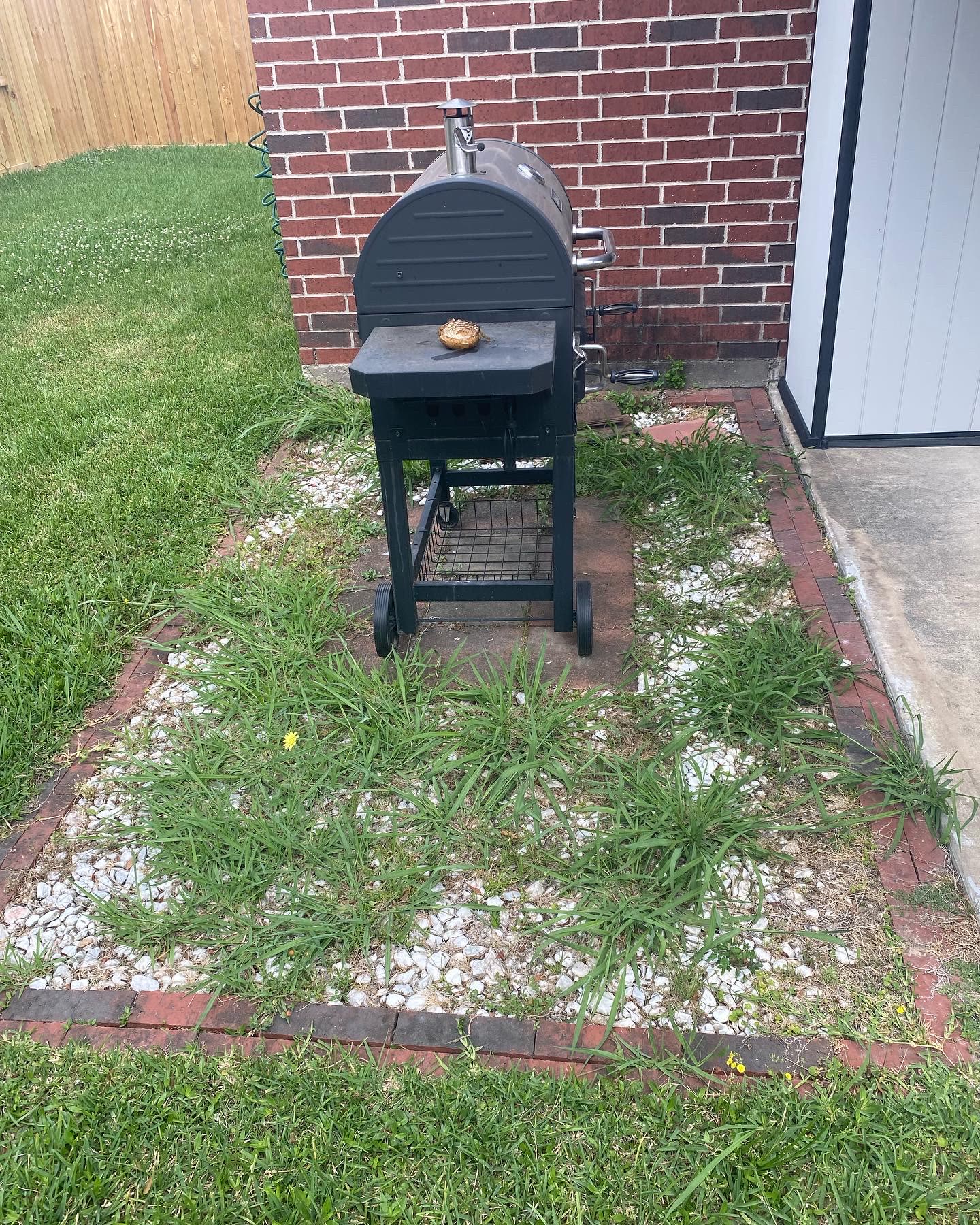 Gravel and grass area beside a brick home before the new concrete pad
