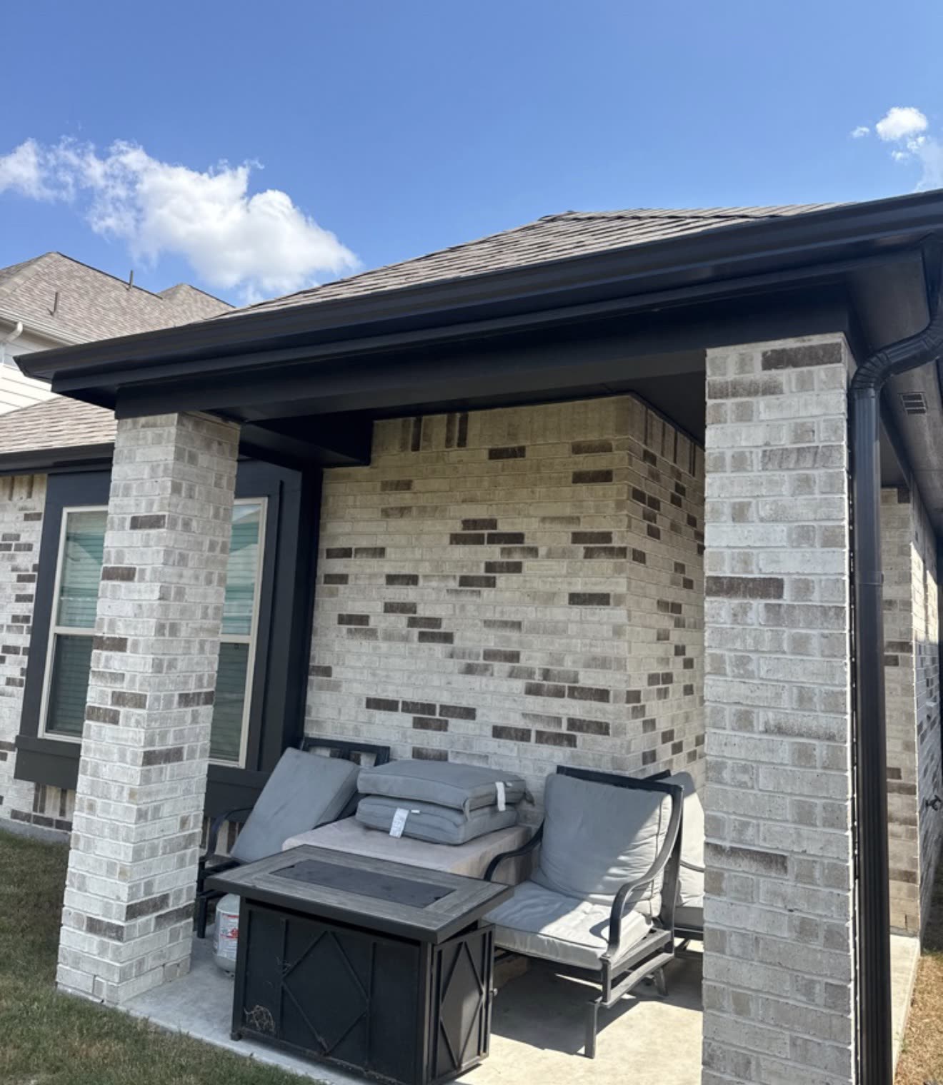 Dark bronze gutters on a covered patio of a light brick home
